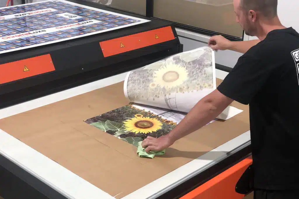 Man standing over a photo of a flower in a factory chromaluxe hd metal printing